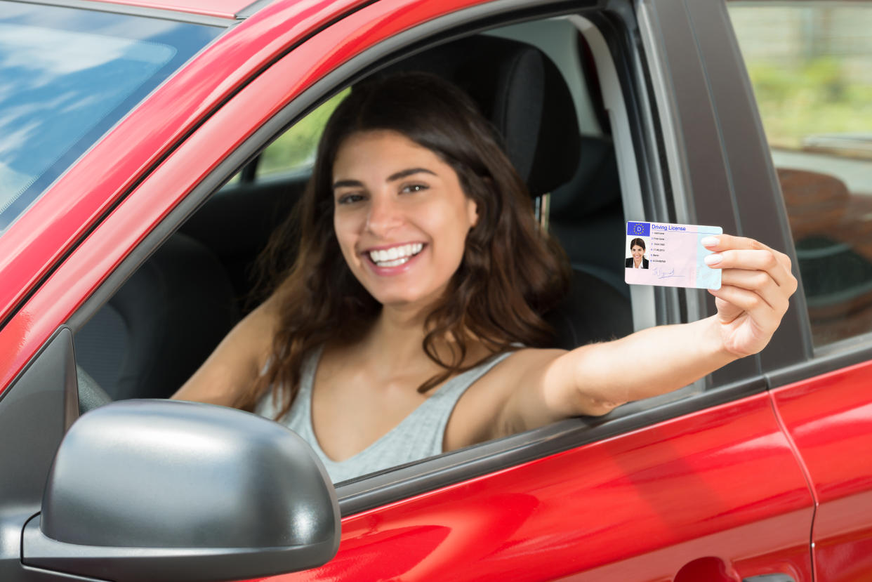 Smiling Young Woman Showing Her Driving License From Open Car Window