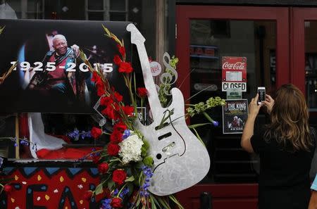 A woman takes a photo of the closed sign next to a small memorial set up in front of the B.B. King Blues Club in Memphis, Tennessee May 27, 2015. REUTERS/Mike Blake