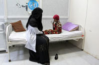 Saida Ahmad Baghili, 18, who has been affected by severe malnutrition, drinks water as she sits with a nurse on a bed at the al-Thawra hospital in the Red Sea port city of Hodeidah, Yemen November 26, 2016. REUTERS/Abduljabbar Zeyad