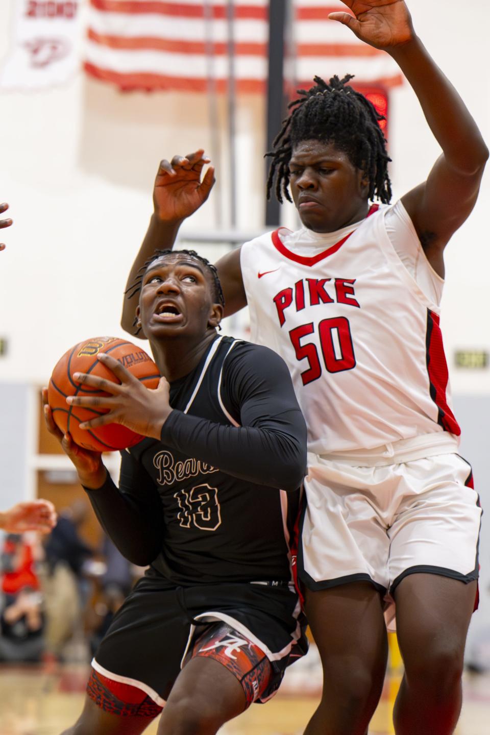 Lawrence Central High School sophomore Albert Gooden III (13) attempts to score while being defended by Pike High School sophomore Muna Newman (50) during the first half of an IHSAA basketball game, Friday, Dec. 15, 2023, at Pike High School.