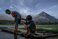 <p>Children fish as Mayon volcano spews ash and lava on January 17, 2018 in Camalig, Albay, Philippines. (Photo: Jes Aznar/Getty Images) </p>