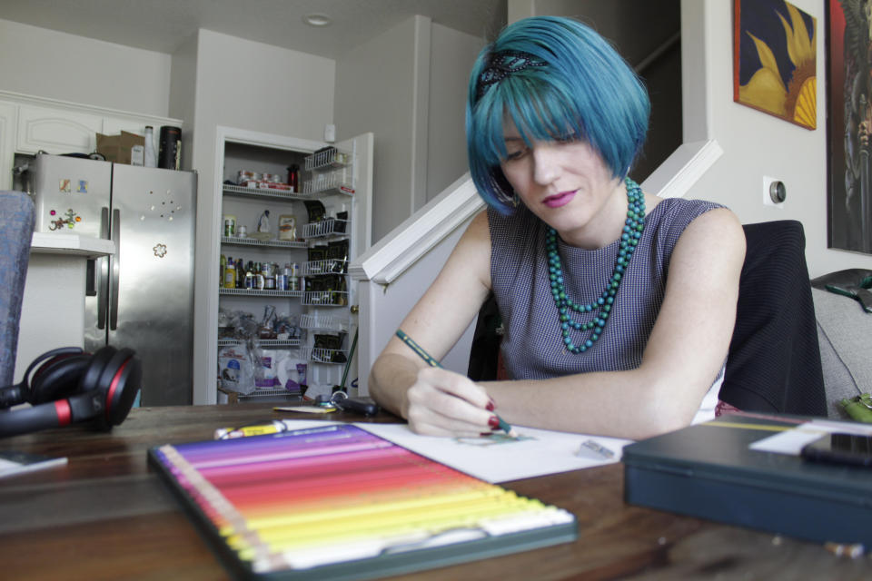 Lynn Hunt, who took out between $45,000 and $50,000 in student loans and was a Pell Grant recipient, uses colored pencil to fill in a sketch at home in Beaverton, Ore., on Wednesday, Aug. 24, 2022. Hunt says President Biden's student loan forgiveness plan isn't enough to help because Hunt owes about $70,000 due to a 6.7% interest rate on the loans. Hunt says the temporary moratorium on loan repayment during the COVID-19 pandemic allowed Hunt to stop working 80-hour weeks and to return to artistic hobbies. (AP Photo/Gillian Flaccus)