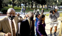 Ahmaud Arbery's father Marcus Arbery, center, heads into the Glynn County Courthouse in Brunswick, Ga with his attorney Benjamin Crump on Monday, Oct. 18, 2021. Jury selection got underway with hundreds of people ordered to report for what could be a long, laborious effort to find jurors to hear the trial of three white men charged with fatally shooting Ahmaud Arbery as he was running in their neighborhood. (AP Photo/Lewis M. Levine)