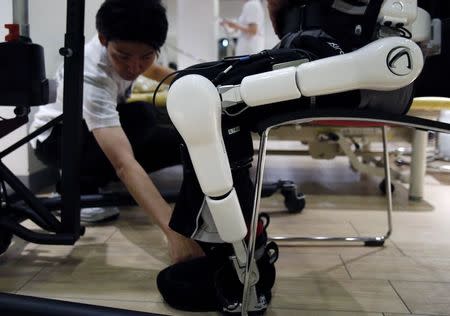 A studio staff from Japan's robot venture company Cyberdyne adjusts the position of the Lower Limb Model HAL (Hybrid Assistive Limb) for welfare use during a HAL training at the Cyberdyne studio in Tsukuba, north of Tokyo July 22, 2014. REUTERS/Yuya Shino