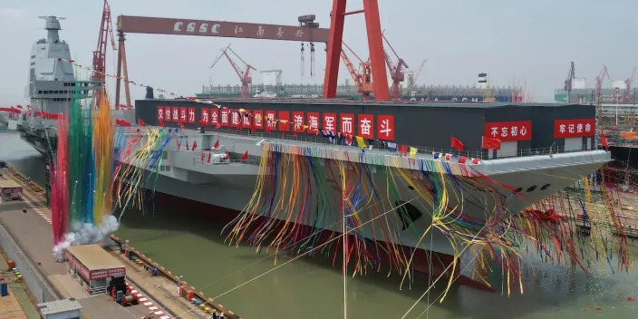 An aircraft carrier covered in streamers at a shipyard