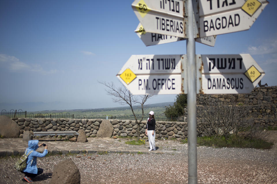 Tourists pose for photograph next to a mock road sign for Damascus, the capital of Syria, and other capitals and cities and a cutout of a soldier, in an old outpost in the Israeli controlled Golan Heights near the border with Syria, Friday, March 22, 2019. President Donald Trump abruptly declared Thursday the U.S. will recognize Israel's sovereignty over the disputed Golan Heights, a major shift in American policy that gives Israeli Prime Minister Benjamin Netanyahu a political boost a month before what is expected to be a close election.(AP Photo/Ariel Schalit)