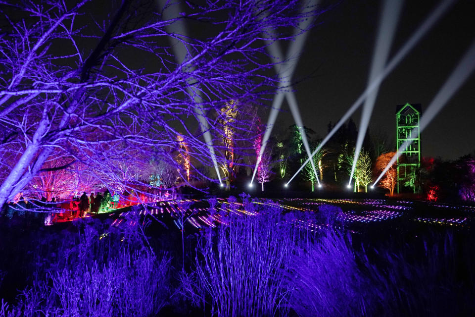 Visitors to the Chicago Botanic Garden's fifth annual Lightscape experience in light and music walk past the 4,800 individually controlled LED light balls of "Sea of Light," created by UK artist Ithaca, in Glencoe, Ill., on Thursday, Dec. 14, 2023. (AP Photo/Charles Rex Arbogast)