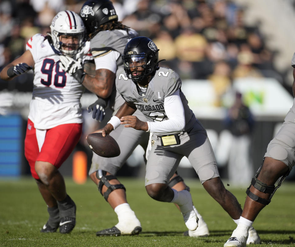 Colorado quarterback Shedeur Sanders (2) eludes Arizona defensive lineman Tiaoalii Savea, back left, as he is tied up by Colorado offensive tackle Ben Reznik in the second half of an NCAA college football game on Saturday, Nov. 11, 2023, in Boulder, Colo. (AP Photo/David Zalubowski)