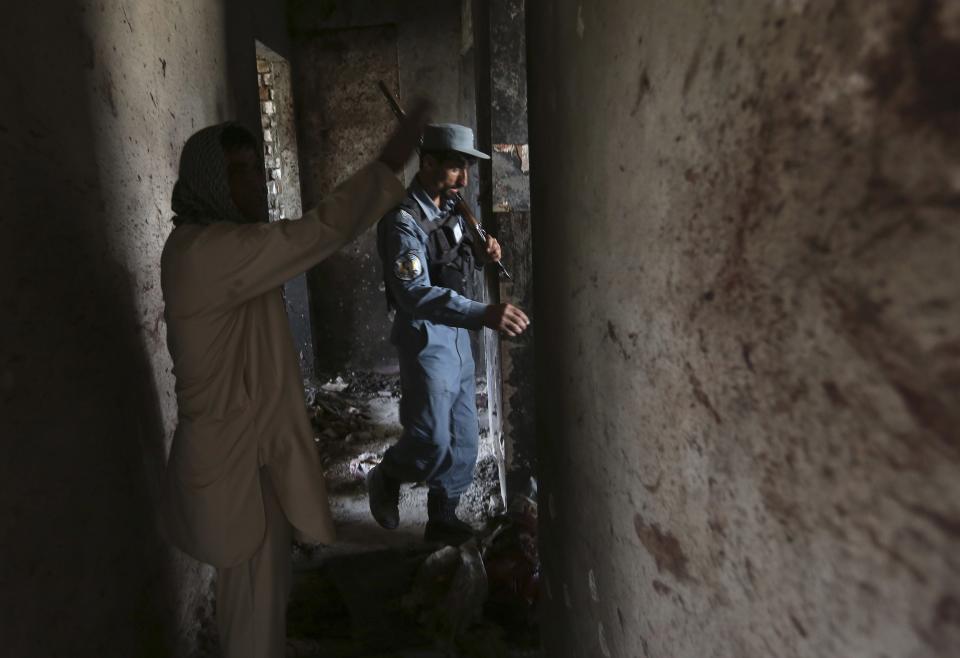 An Afghan policeman stands next to bloodstains at a building, where four unidentified militants were located at, after an attack in Kabul