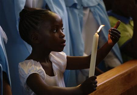 A girl holds a candle during a service for former South African President Nelson Mandela, in the Regina Mundi Church in Soweto December 8, 2013. REUTERS/Kevin Coombs