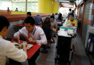 Cleaner Mary Lim, 71, clears tables at a food centre in Singapore December 13, 2018. REUTERS/Edgar Su/Files