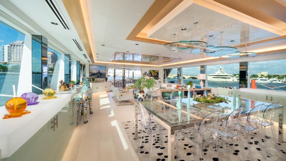 Not your usual superyacht salon: Cloud chandeliers over the glass dining table, a full-sized papier mâché Great Dane and paw-print custom carpeting define tintin.  - Credit: Courtesy Fraser Yachts