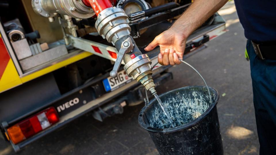 Einsatzkräfte der Freiwilligen Feuerwehr Lauenau zapfen Löschwasser aus dem Tank eines ihrer Einsatzfahrzeuge.