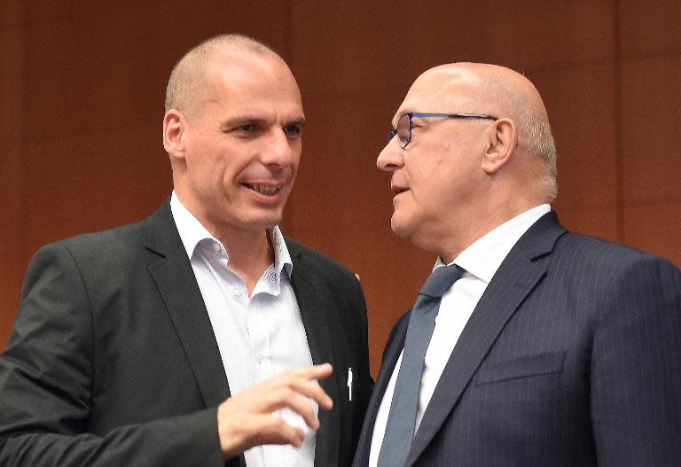 French Finance Minister Michel Sapin (R) and Greece's Finance Minister Yanis Varoufakis speak at the start of an Eurogroup meeting at the European Council in Brussels, on May 11, 2015