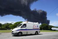 An ambulance drives away from the Matanzas Supertanker Base, where firefighters work to quell a blaze which began during a thunderstorm the night before, in Matazanas, Cuba, Saturday, Aug. 6, 2022. The fire at an oil storage facility raged uncontrolled Saturday, where four explosions and flames injured nearly 80 people and left over a dozen firefighters missing, Cuban authorities said. (AP Photo/Ramon Espinosa)