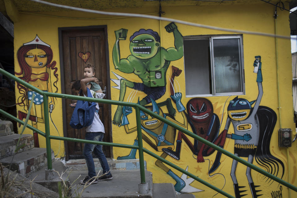 A boy is carried upstairs along the "Graffiti Way" at the Prazeres slum in Rio de Janeiro, Brazil, Friday, March 28, 2014. Dozens of houses were painted by local and international Graffiti artists, creating a colorful path all the way to the top of the community. (AP Photo/Felipe Dana)