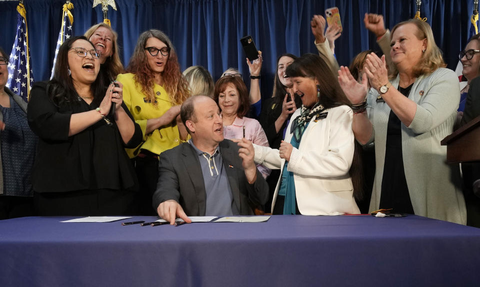 Colorado Gov. Jared Polis, front center, is applauded by, state Sen. Julie Gonzales, far left, state Rep. Brianna Titone, second from left, Lt. Gov. Dianne Primavera, third from left, state Sen. Sonya Jaquez Lewis and state Rep. Meg Froelich after he signed the first of three bills that enshrined protections for abortion and gender-affirming care procedures and medications during a ceremony with bill sponsors and supporters, Friday, April 14, 2023, in the State Capitol in Denver. (AP Photo/David Zalubowski)