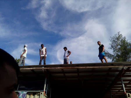 Asylum seekers occupying the closed Australian-run immigration detention centre on Papua New Guinea's Manus Island climb on top of buildings at the centre to avoid police, November 23, 2017. Thanus/via REUTERS