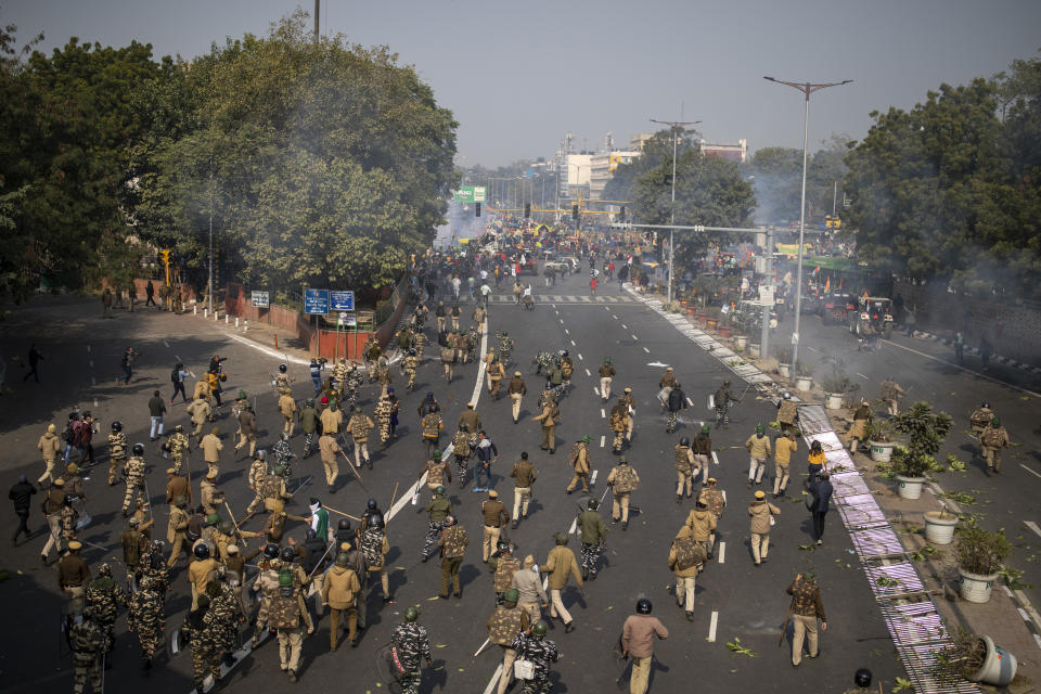 Indian police chase protesting farmers away as they march to the capital breaking police barricades during India's Republic Day celebrations in New Delhi, India, Tuesday, Jan. 26, 2021. Tens of thousands of farmers drove a convoy of tractors into the Indian capital as the nation celebrated Republic Day on Tuesday in the backdrop of agricultural protests that have grown into a rebellion and rattled the government. (AP Photo/Altaf Qadri)