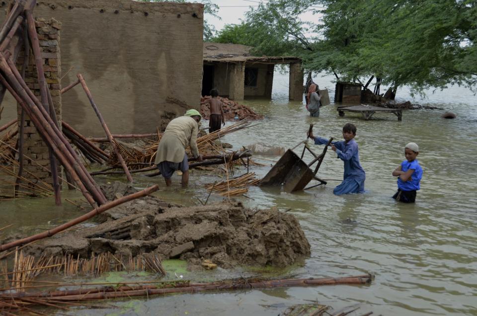 A family salvage usable items from their flood-hit home in Jaffarabad, a district of Pakistan's southwestern Baluchistan province, Thursday, Aug. 25, 2022. Pakistan's government in an overnight appeal sought relief assistance from the international community for flood-affected people in this impoverished Islamic nation, as the exceptionally heavier monsoon rain in recent decades continued lashing various parts of the country. (AP Photo/Zahid Hussain)