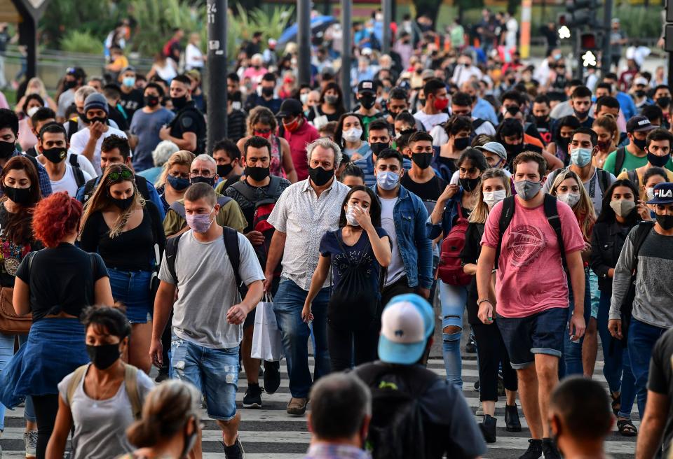 People wearing protective face masks walk by the Brazil Avenue, near the Constitucion train station, in Buenos Aires, on April 6, 2021. - Covid-19 infections in the last 24 hours in Argentina rose to 20,870, a record since the beginning of the coronavirus pandemic, the Ministry of Health reported on Tuesday, April 6. (Photo by RONALDO SCHEMIDT / AFP) (Photo by RONALDO SCHEMIDT/AFP via Getty Images)