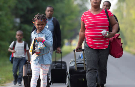 A family that stated they are from Haiti walk to the US-Canada border to cross into Canada from Champlain, New York, U.S. August 11, 2017. REUTERS/Christinne Muschi