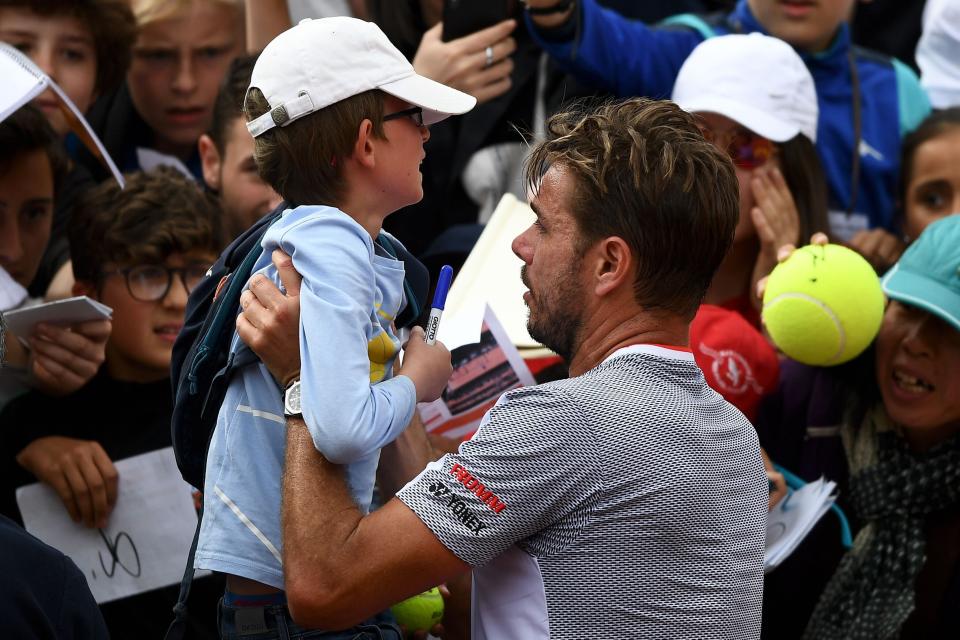 Switzerland's Stanislas Wawrinka holds a young fan in his arms as he signs autographs at the end of his men's singles second round match against Chile's Christian Garin on day four of The Roland Garros 2019 French Open tennis tournament in Paris on May 29, 2019. (Photo by Anne-Christine POUJOULAT / AFP)        (Photo credit should read ANNE-CHRISTINE POUJOULAT/AFP/Getty Images)