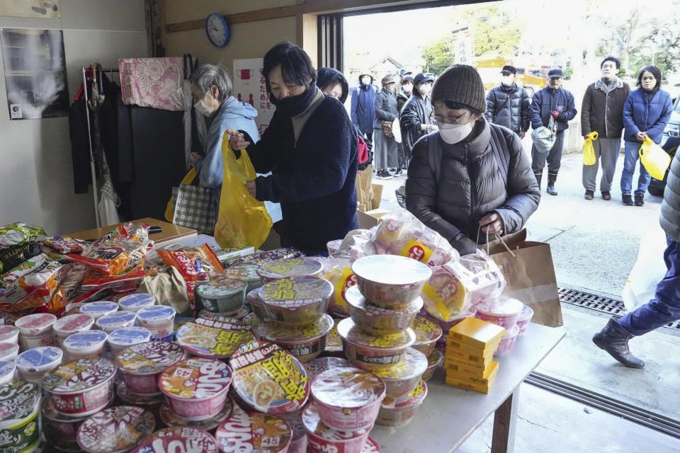 People affected by a strong earthquake receive food in Wajima, Ishikawa prefecture, Japan Friday, Jan. 5, 2024. Monday’s temblor decimated houses, twisted and scarred roads and scattered boats like toys in the waters, and prompted tsunami warnings. (Kyodo News via AP)