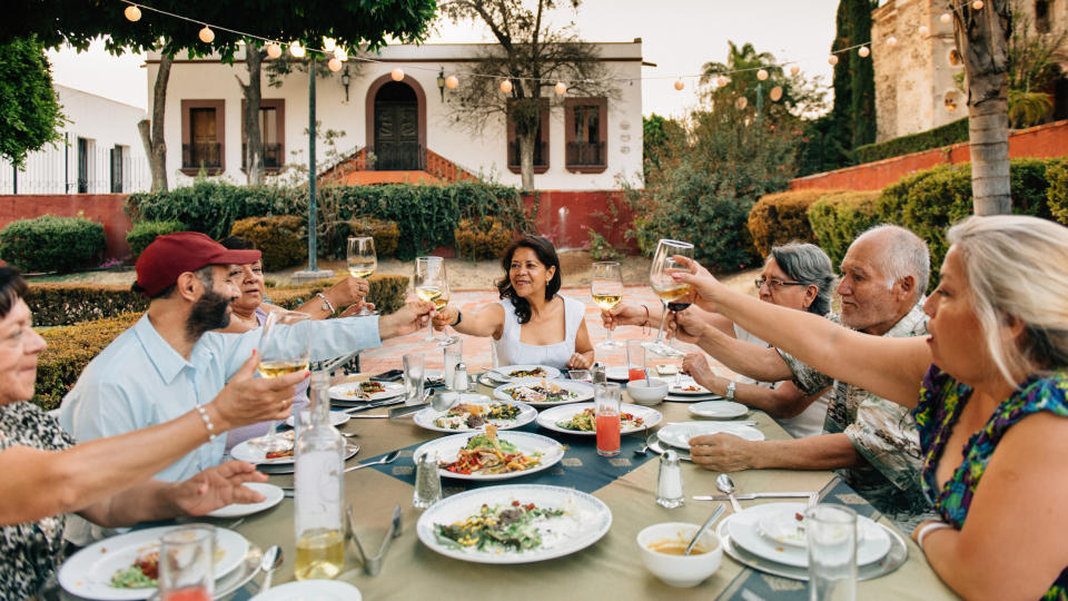 a large group of people eating at a table and raising their glasses