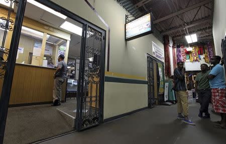 Shakir Hussein (L), owner of money transfer business Mustaqbal Express, wires money for Mohammed Ahamed (at counter) for Ahamed's former wife in Somalia, in Minneapolis June 23, 2014. REUTERS/Eric Miller