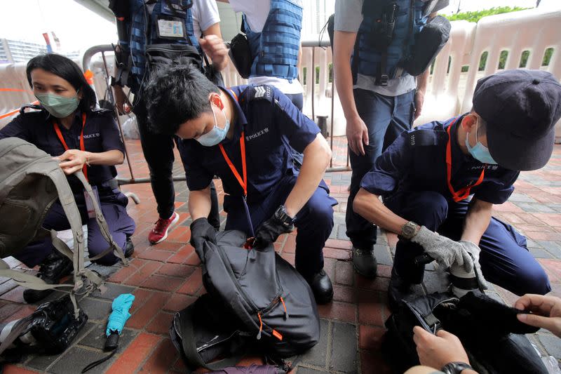 Police officers inspect journalists' bags outside Hong Kong West Kowloon railway station