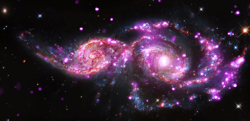 The photo is a composite image of the spiral galaxies <a href="http://www.nasa.gov/mission_pages/chandra/galactic-get-together-has-impressive-light-display.html#.VIn_HifwP4j" target="_blank">NGC 2207 and IC 2163</a>, located 130 million light years away in the constellation Canis Major. The image contains data from the Chandra X-ray Observatory in pink, optical light data from the Hubble Space Telescope in red, green, and blue, and infrared data from the Spitzer Space Telescope in red.