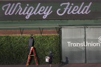 A Chicago Cubs employee retrieves a baseball from the right field basket after batting practice and before a baseball game between the Chicago Cubs and the Kansas City Royals Tuesday, Aug. 4, 2020, in Chicago. (AP Photo/Charles Rex Arbogast)