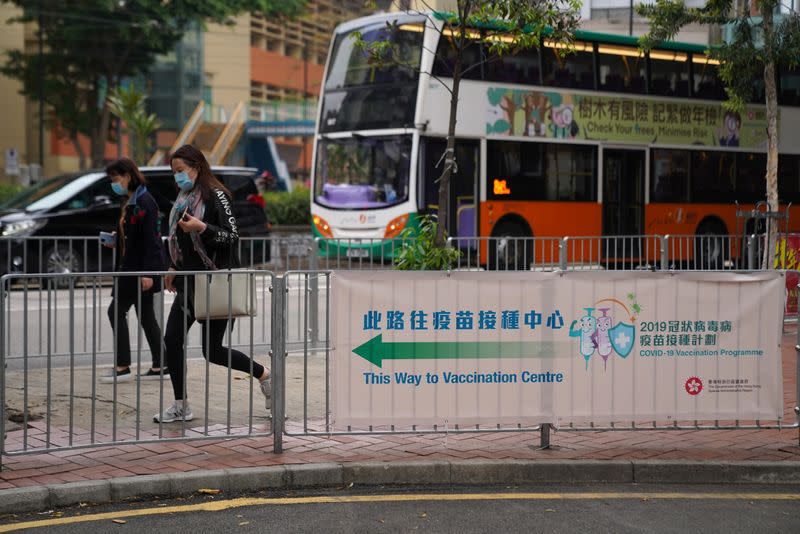 Pedestrians pass by a banner directing the way to a site for coronavirus disease (COVID-19) vaccination in Hong Kong