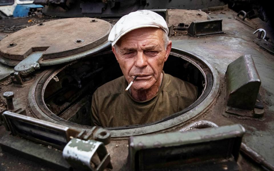 A Ukrainian serviceman, 66-year-old Ihor, pokes his head up from the hatch of a captured Russian BMP-2 infantry fighting vehicle that he is fixing in Donetsk region on June 16th