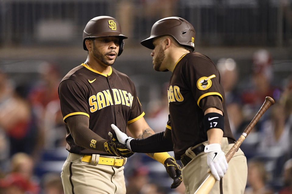 San Diego Padres' Tommy Pham, left, is greeted by Victor Caratini, right, after scoring on a double by Eric Hosmer during the fourth inning of a baseball game against the Washington Nationals, Friday, July 16, 2021, in Washington. (AP Photo/Nick Wass)