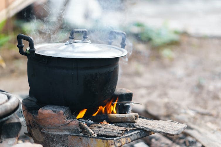 A clay pot on top of smouldering charcoal fuel.