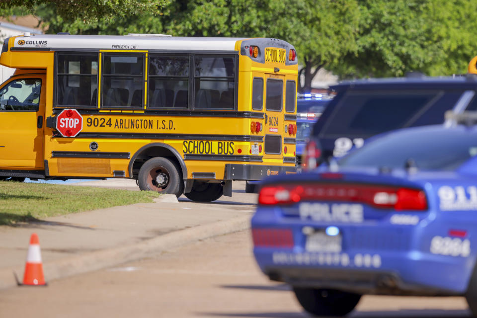 Police vehicles and school buses are prepared to escort students to be reunited with their families at Arlington Bowie High School after the school was placed on a lockdown due to a suspected shooting outside the school building, Wednesday April 24, 2024, in Arlington, Texas. (AP Photo/Gareth Patterson)