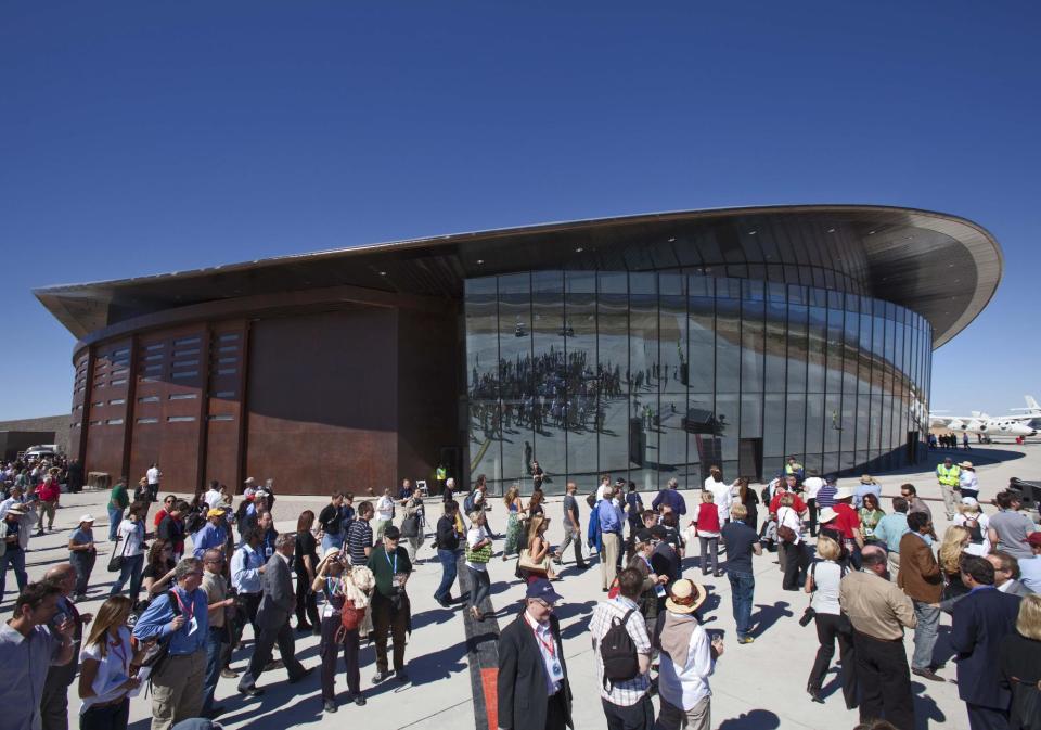 FILE - In this Oct. 17, 2011 file photo, guests stand outside the new Spaceport America hangar in Upham, N.M. With Spaceport nearly complete but still mostly empty, Branson and Virgin Galactic has hinted it may take its spacecraft and launch elsewhere. (AP Photo/Matt York, File)