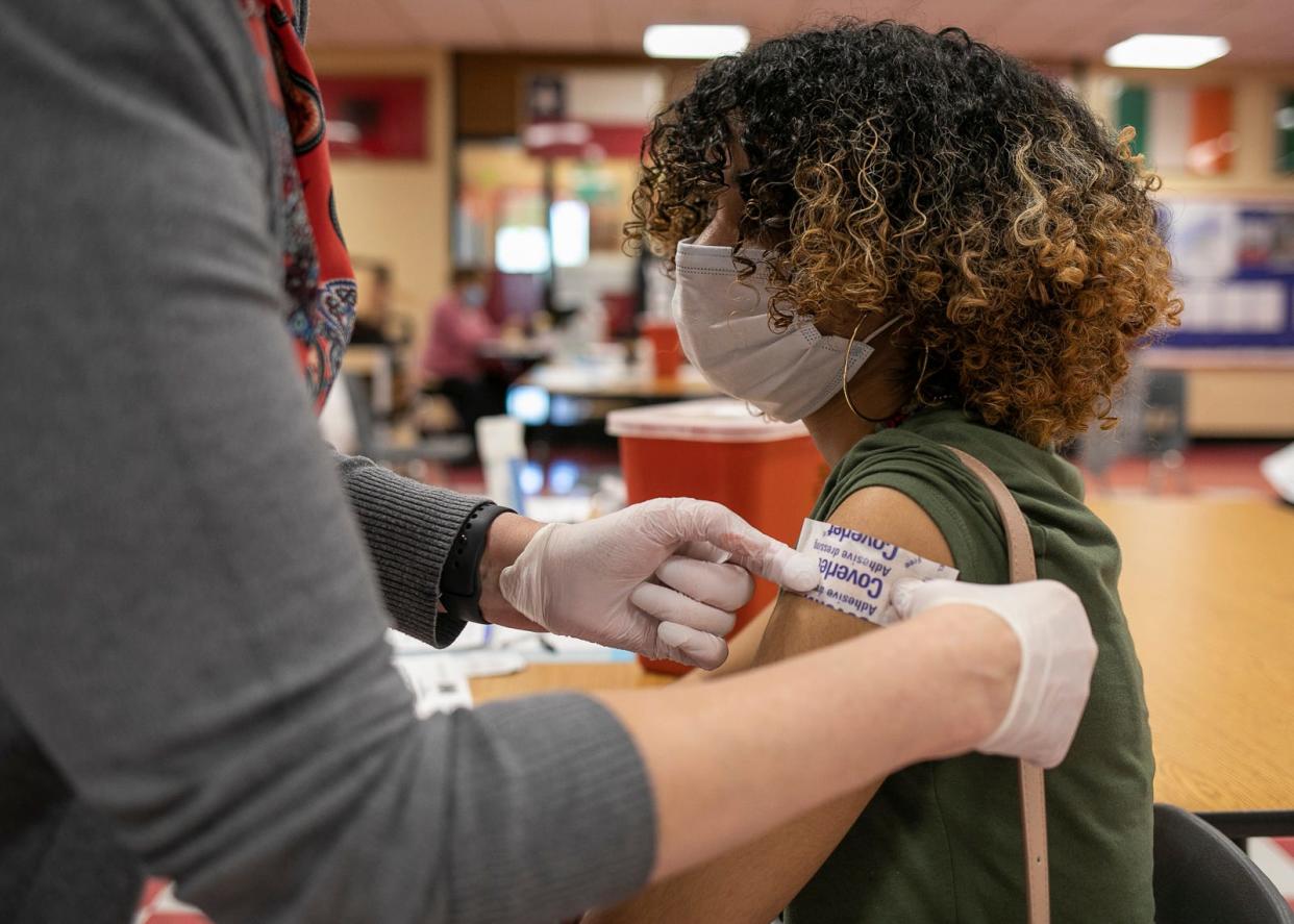 Brockton Public Schools nursing supervisor Linda Cahill puts a bandaid on the arm of Micaelle Nunes, 16, after administering a Pfizer COVID-19 vaccine in the red cafeteria at Brockton High School on Thursday, May 6, 2021. 