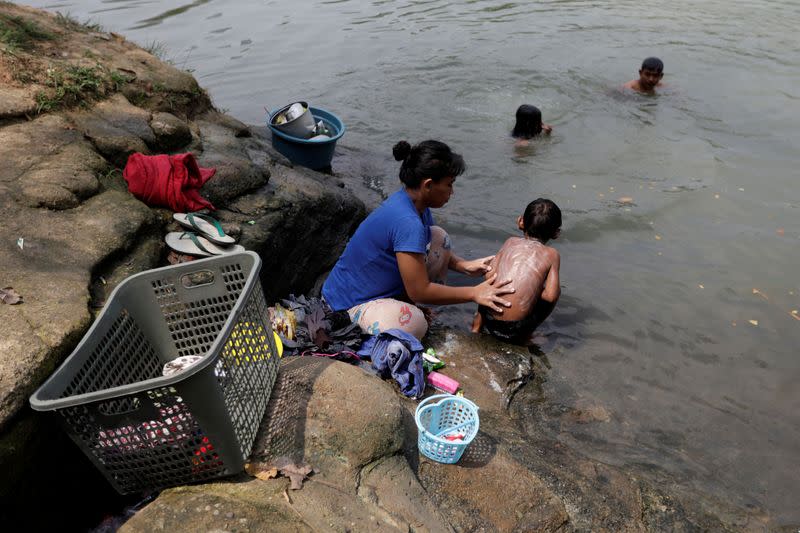 Ratna, 23-year-old local, bathes her 6-year-old son Muhammad Teguh Sidik, as she washes clothes at Cisadane river in Tangerang