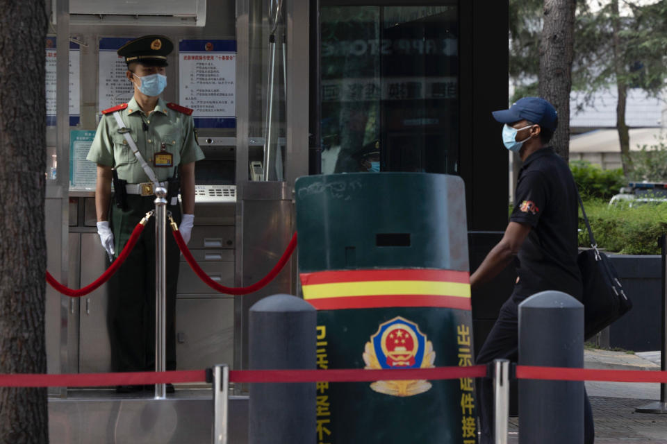 A Chinese paramilitary policeman looks on as a consular staff member walks past the United States Consulate in Chengdu in southwest China's Sichuan province on Sunday, July 26, 2020. China ordered the United States on Friday to close its consulate in the western city of Chengdu, ratcheting up a diplomatic conflict at a time when relations have sunk to their lowest level in decades. (AP Photo/Ng Han Guan)