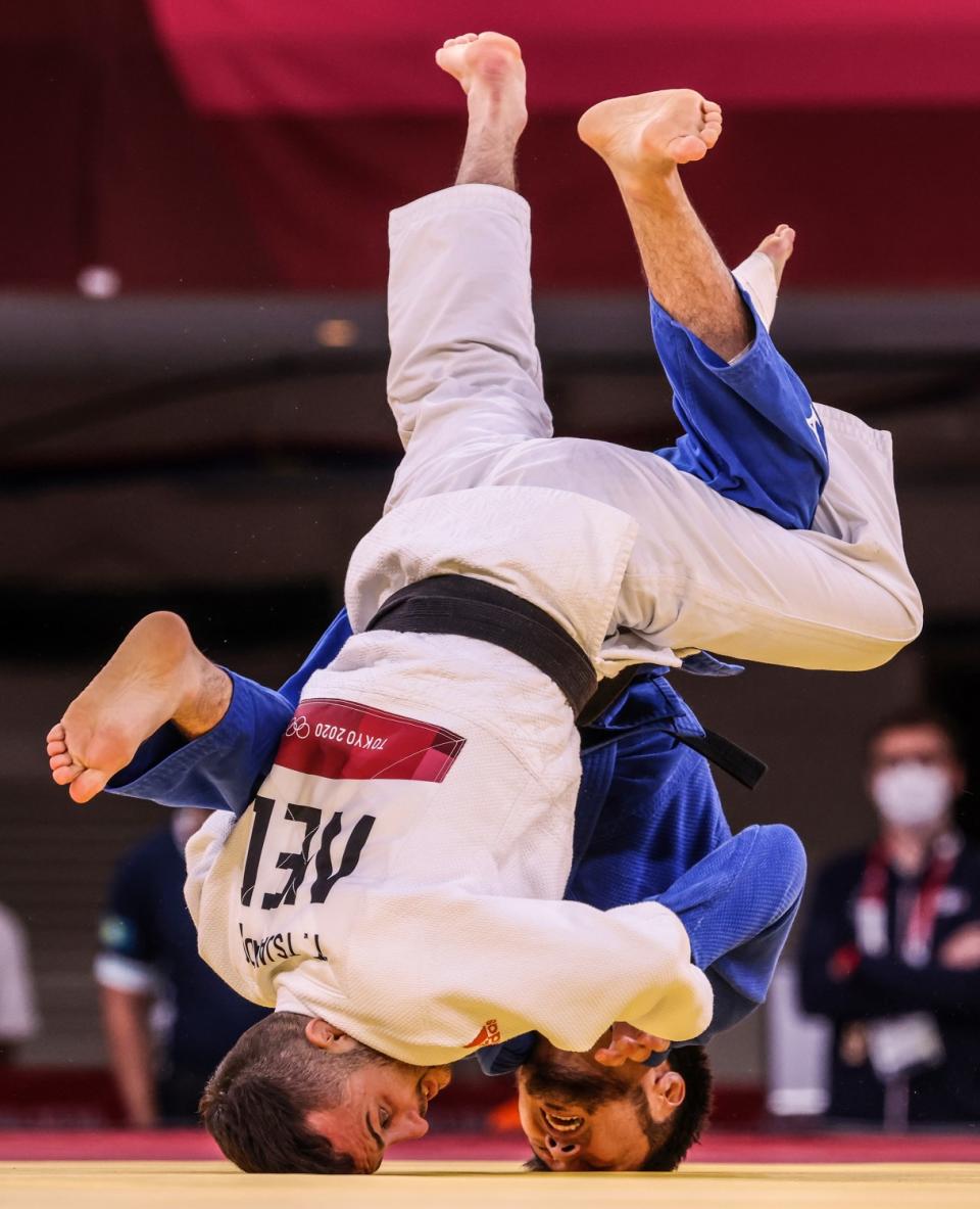 Two martial artists grapple while upside down and poised on their heads.