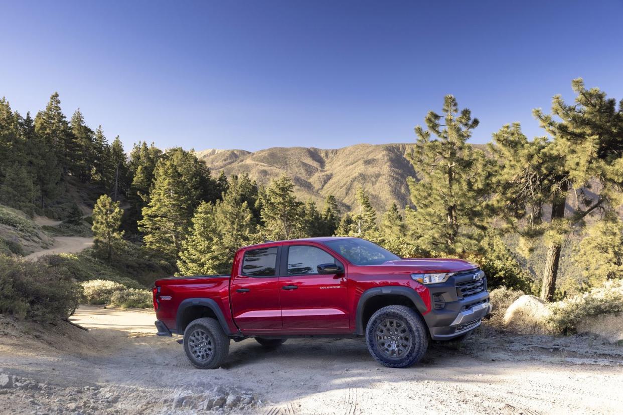 side view of colorado trail boss in scenic area with mountains, trees and a dirt road