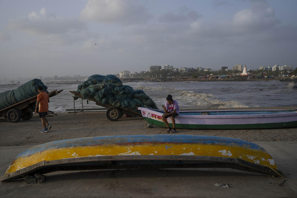 A boy sits on a boat on shore as high tide waves hit the Arabian Sea coast at Juhu Koliwada in Mumbai, India, Monday, June 12, 2023. Cyclone Biparjoy, the first severe cyclone in the Arabian Sea this year is set to hit the coastlines of India and Pakistan Thursday. (AP Photo/Rafiq Maqbool)