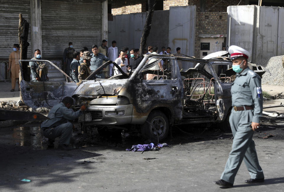 Afghan security personnel inspect the site of a bomb explosion in Kabul, Afghanistan, Saturday, June 12, 2021. Separate bombs hit two minivans in a mostly Shiite neighborhood in the Afghan capital Saturday, killing several people and wounding others, the Interior Ministry said. (AP Photo/Rahmat Gul)