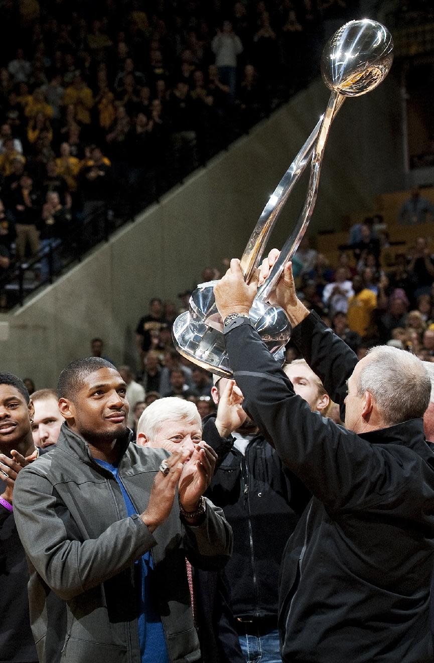 Missouri's All-American defensive end Michael Sam, left, watches head coach Gary Pinkel, right, raise the Cotton Bowl trophy during a presentation at halftime of an NCAA college basketball game between Missouri and Tennessee, Saturday, Feb. 15, 2014, in Columbia, Mo. Sam came out to the entire country Sunday, Feb. 9, and could become the first openly gay player in the NFL. (AP Photo/L.G. Patterson)