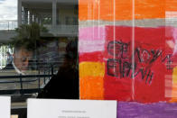 A painting by a primary school student is seen on a classroom window with writing reading in Greek "We need Peace" as a man casts his vote during the presidential elections in Geroskipou in south west coastal city of Paphos, Cyprus, Sunday, Feb. 5, 2023. Cypriots began voting for their eighth new president in the ethnically divided island’s 62-year history as an independent republic, with three front-runners each portraying themselves as the safest bet to guide the country through turbulent economic times and to seek peace with breakaway Turkish Cypriots. (AP Photo/Petros Karadjias)