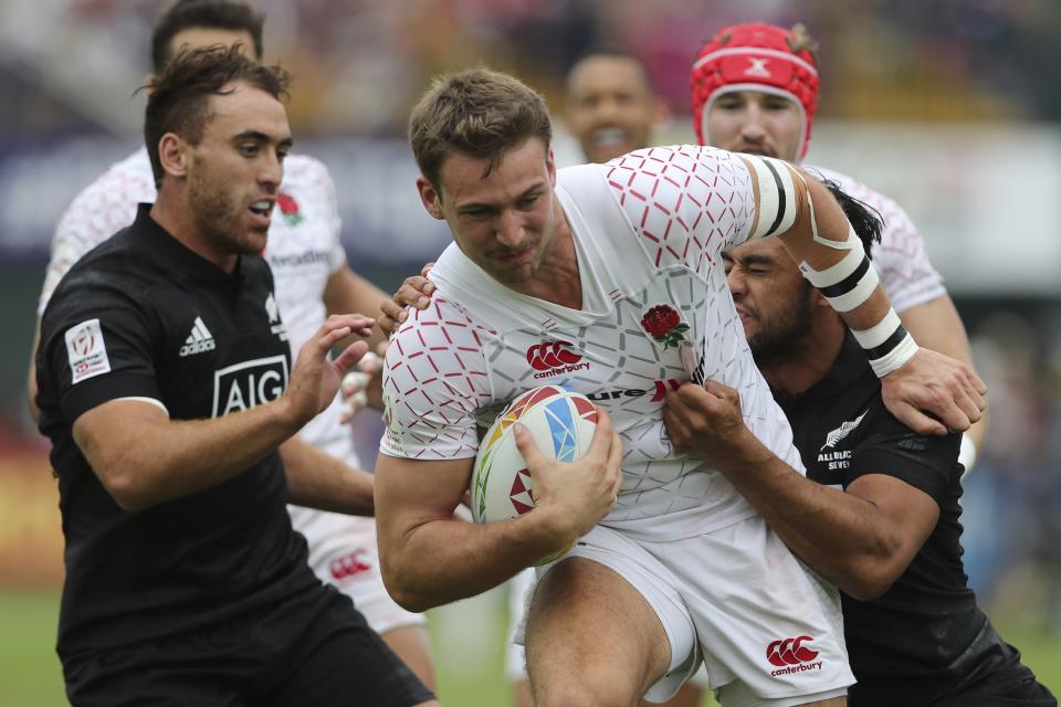 England's Harry Glover runs with the ball as New Zealand's players try to stop him during a semi final match of the Emirates Airline Rugby Sevens in Dubai, United Arab Emirates, Saturday, Dec. 7, 2019. (AP Photo/Kamran Jebreili)