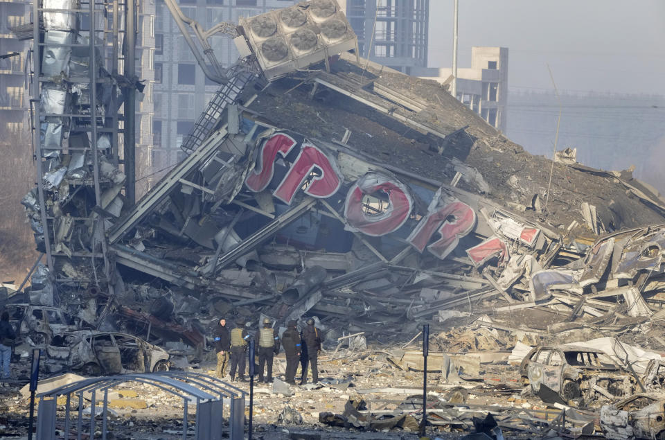 People examine the damage after shelling of a shopping center, in Kyiv, Ukraine, Monday, March 21, 2022. Eight people were killed in the attack. (AP Photo/ (AP Photo/Efrem Lukatsky)